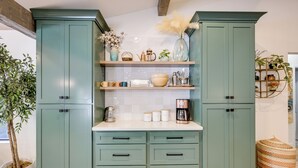Una cocina con armarios color turquesa, encimeras blancas y diversos utensilios de cocina.