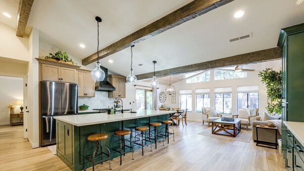 Una cocina amplia con una isla grande, taburetes de bar de madera y un comedor con mesa y sillas.