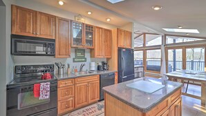 A modern kitchen with wooden cabinets, a black stove, a microwave, and a refrigerator. - Locust Lake Village Cabin w/ Deck & Lake View! (Pocono Lake)