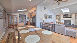 A spacious kitchen with wooden cabinets, a central island, and a dining area with a long table. - Locust Lake Village Cabin w/ Deck & Lake View! (Pocono Lake)