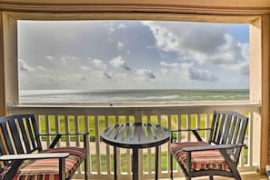 Ein Balkon mit Meerblick, zwei Stühle und ein kleiner Tisch.