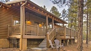 A log cabin with a porch, outdoor seating, and a staircase leading to the upper level. - Torreon Cabin Escape - Relax, Recharge and Explore (Show Low)