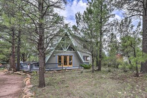 A cabin with a wooden deck, surrounded by pine trees. - Overgaard Cabin w/ Hot Tub, Fire Pit & Deck! (Overgaard)