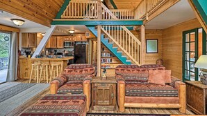 L’intérieur d’une cabane en rondins comprend un espace salon central, une cuisine et un escalier menant à un étage supérieur.