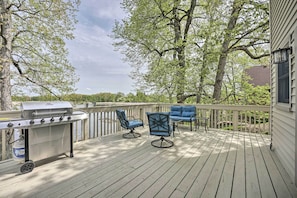 A deck with a grill, two blue chairs, and a table. - Pet-friendly Grass Lake Retreat w/ Game Room! (Grass Lake)