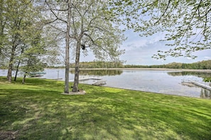 A serene lakeside setting with a dock, trees, and a grassy area. - Pet-friendly Grass Lake Retreat w/ Game Room! (Grass Lake)