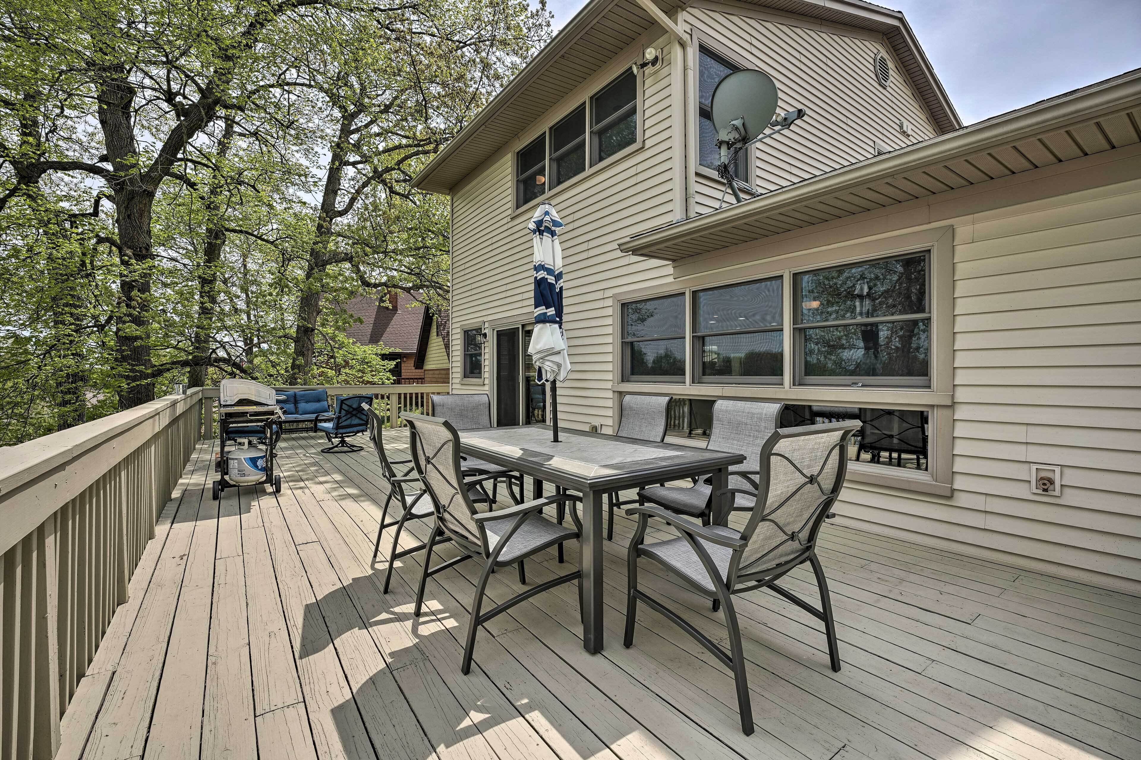Une terrasse en bois avec une table et des chaises, une antenne parabolique sur le toit de la maison et une porte de garage.