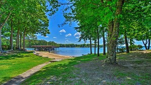 A lakeside park with a covered pavilion, a walking path, and a dock extending into the water.