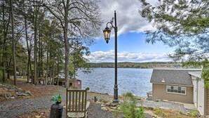 Une vue sur le lac avec un banc, un lampadaire et un petit bâtiment situé près de l’eau.