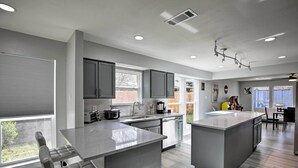 Una cocina moderna con armarios grises, una isla central y una zona de comedor con una silla.