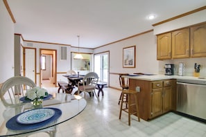 A spacious kitchen with wooden cabinets, a dishwasher, and a dining area with a glass table and chairs.