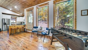A spacious room with a wooden floor, a foosball table, and a bar area with stools. - Furnished Deck, Hot Tub! Family Gem in Broken Bow (Broken Bow)