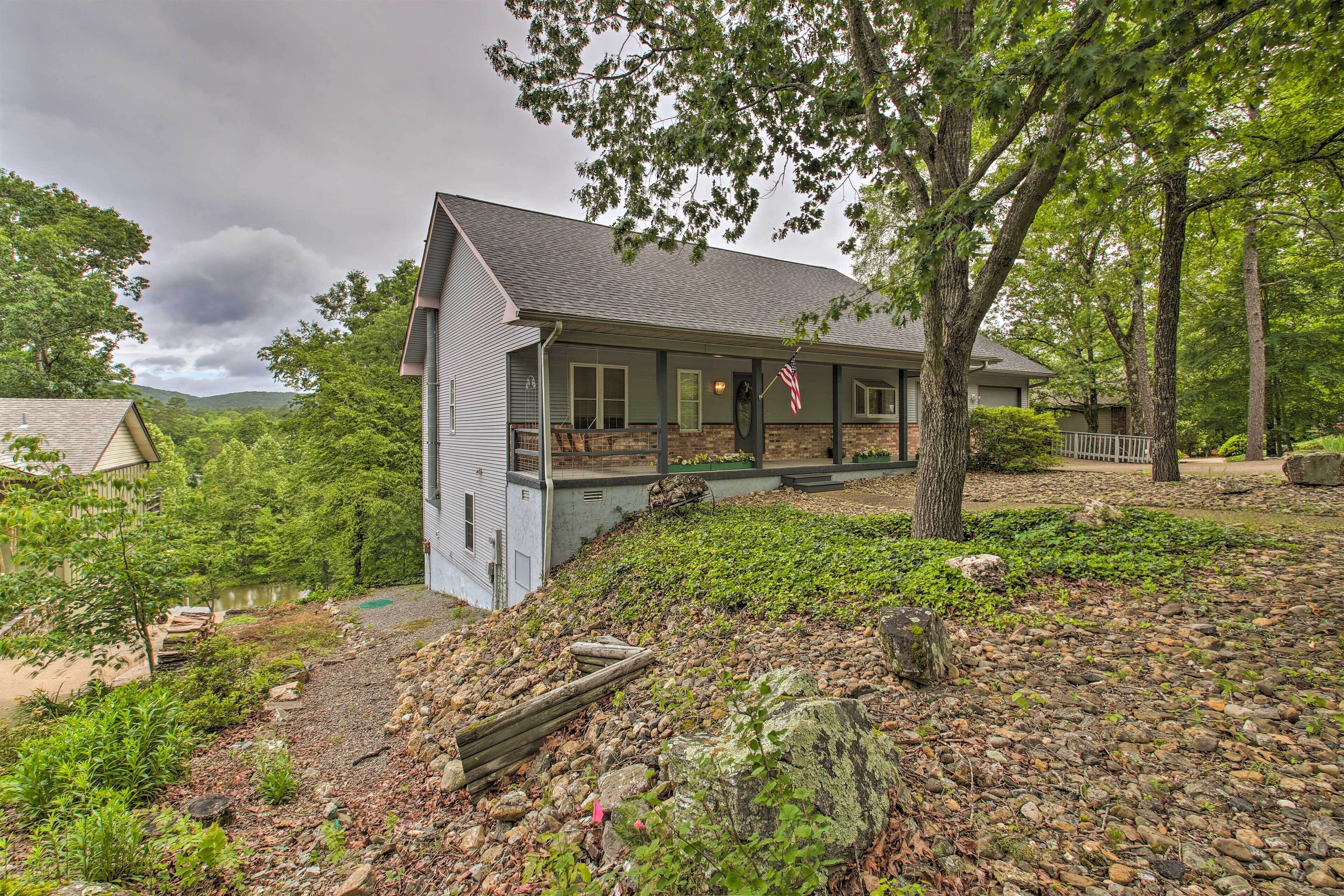 A two-story house with a stone foundation, a porch, and an American flag.