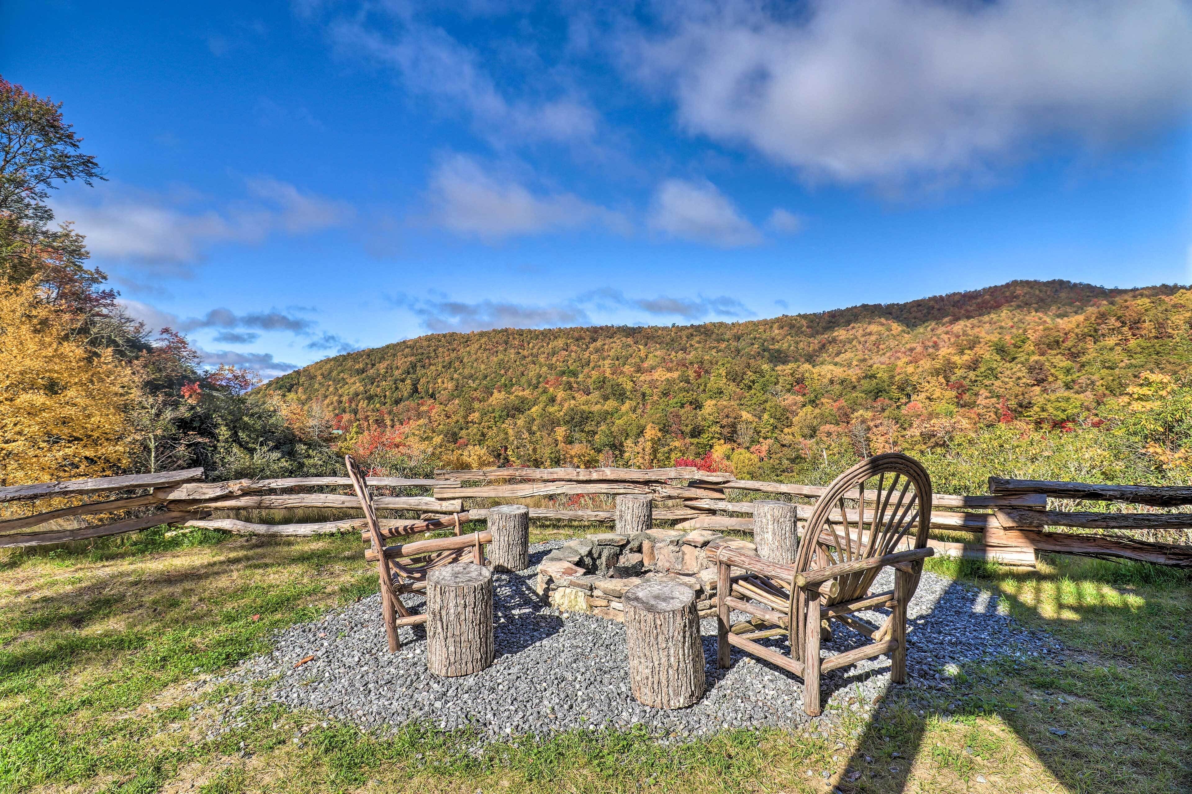 A rustic outdoor seating area with a wooden fence and a fire pit surrounded by logs.