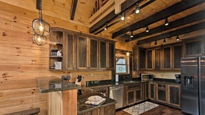 A modern kitchen with wooden walls, built-in cabinets, stainless steel appliances, and a central island. - Hilltop Cabin on 5 Acres w/ Hot Tub & Waterfall! (Bryson City)