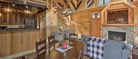 Un intérieur spacieux en bois, comprenant un coin repas, une cheminée et un escalier menant à un niveau supérieur.