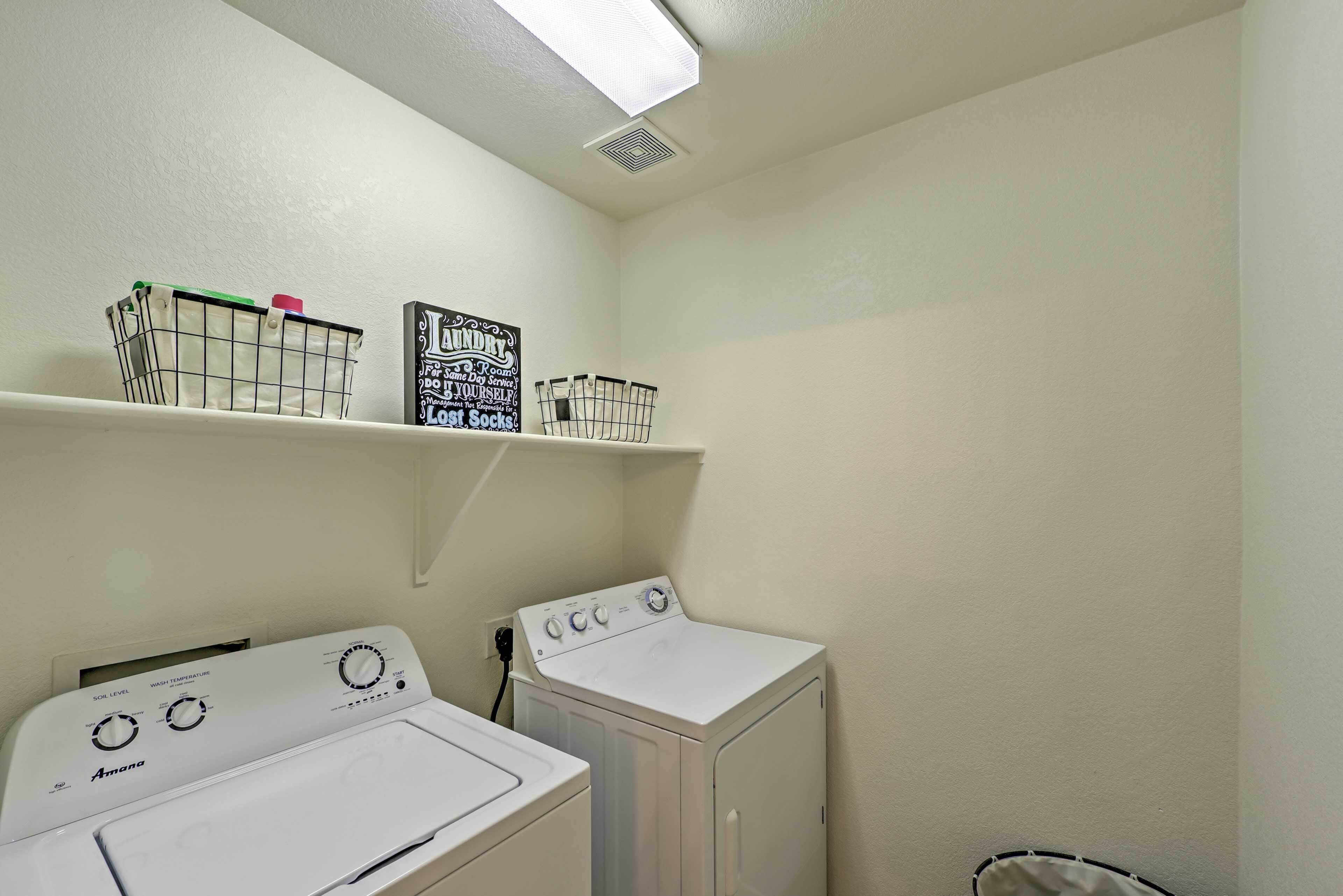 A laundry room with two front-loading washing machines, a shelf with laundry baskets, and a sign with laundry instructions.