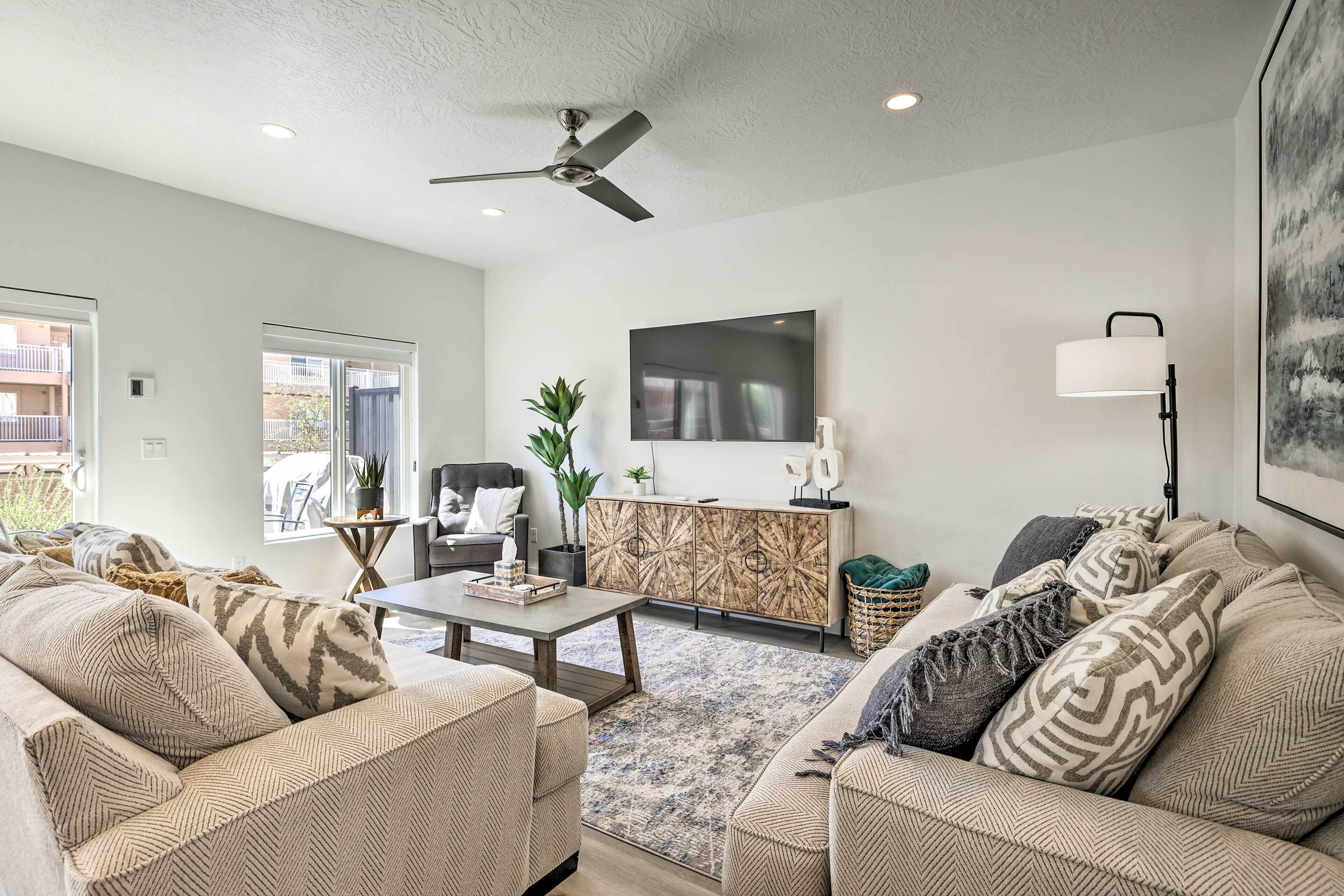 A modern living room with a sofa set, a coffee table, a TV, and a ceiling fan.