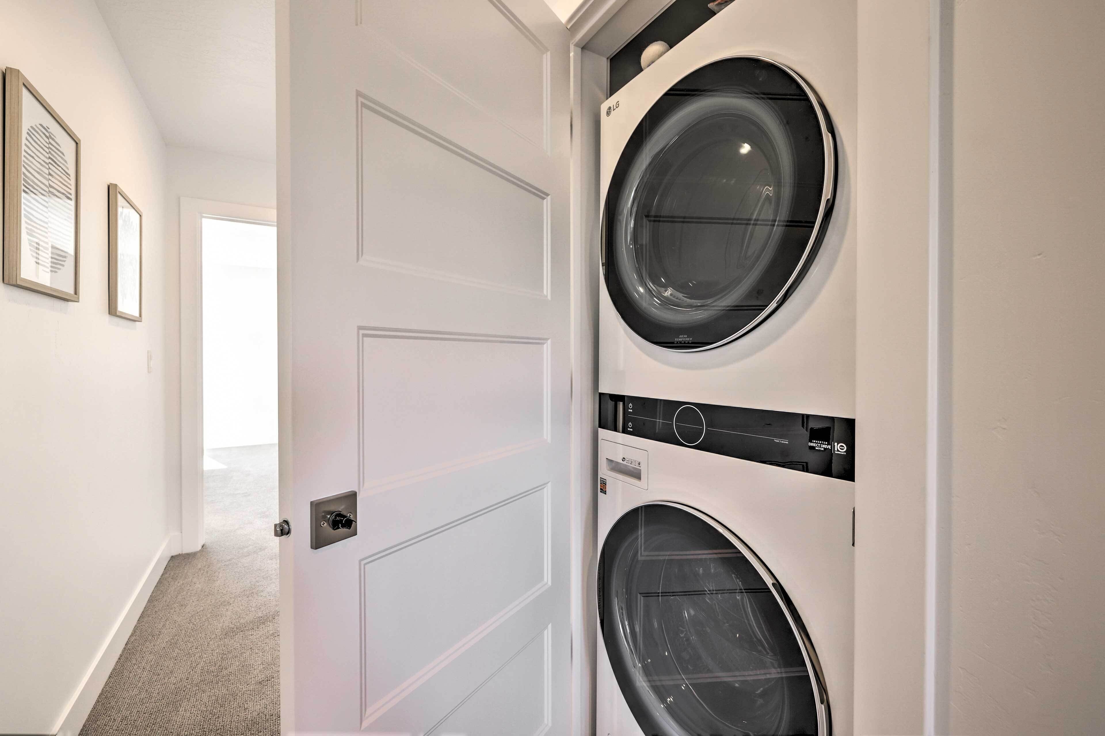 A laundry room with two front-loading washing machines and a door leading to another room.