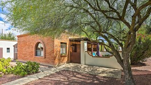 A small brick building with a wooden porch and a large tree in front. - Lovely Green Valley Abode w/ Community Pool! (Green Valley)