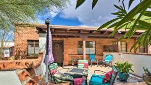 A patio area with a brick wall, outdoor furniture, and potted plants. - Lovely Green Valley Abode w/ Community Pool! (Green Valley)