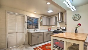 A modern kitchen with a wooden table, a built-in oven, and a clock on the wall. - Lovely Green Valley Abode w/ Community Pool! (Green Valley)