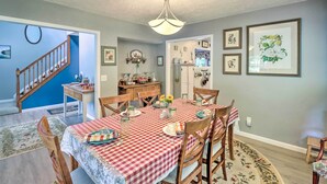 A dining area with a checkered tablecloth, wooden chairs, and a chandelier.