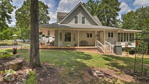 A two-story house with a porch, a covered front porch area, and a small front yard with a tree and a bench.