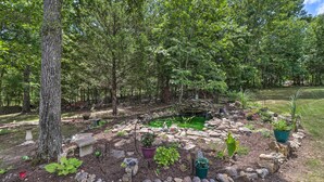A garden with a pond, surrounded by rocks and plants, and a stone bench.