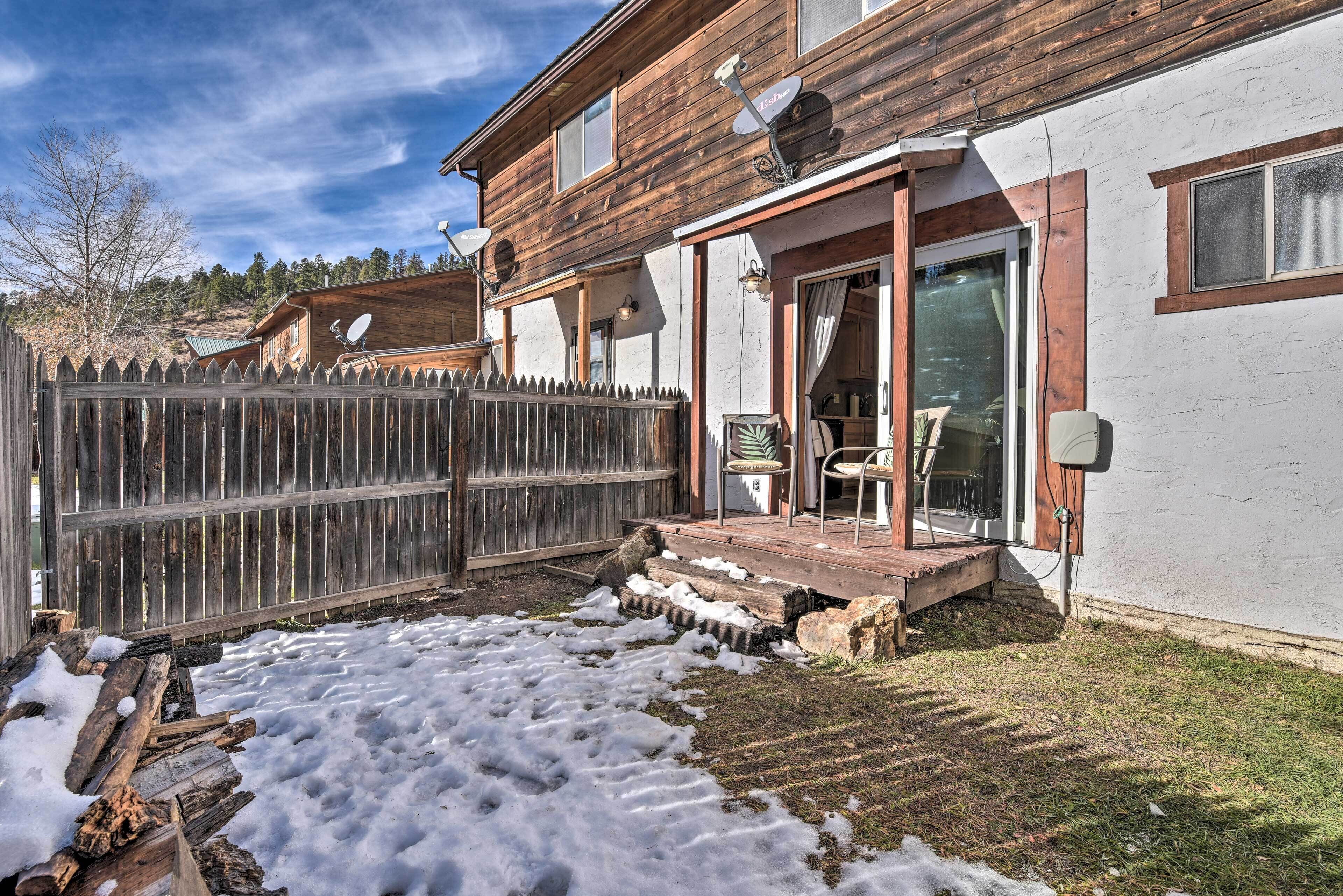Une maison en bois avec un jardin clôturé, une terrasse dotée de mobilier d’extérieur et un garage.