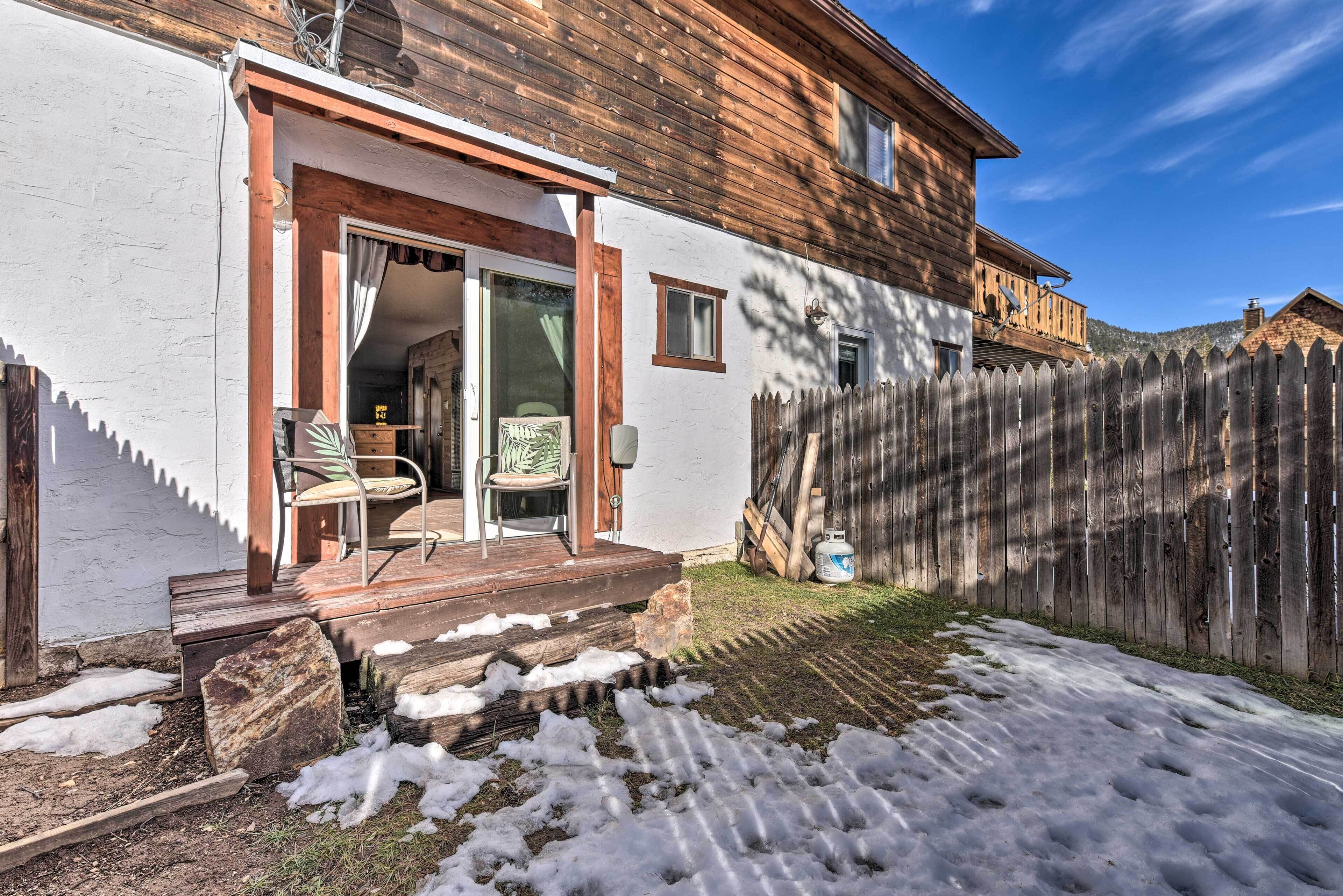 Une maison en bois avec un porche couvert et une cour arrière clôturée.