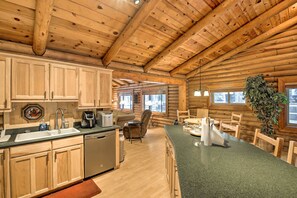 A log cabin interior with a kitchen, dining area, and a large window. - 11 Mi to Rainbow Lake: Family Home w/ Large Yard (Pinetop)