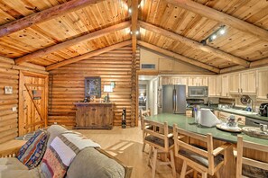 A log cabin interior with a dining area, kitchen, and a cozy living space. - 11 Mi to Rainbow Lake: Family Home w/ Large Yard (Pinetop)