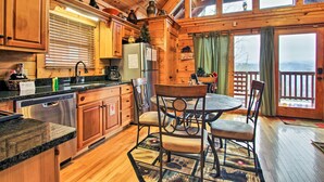 A cabin-style kitchen with wooden cabinets, a refrigerator, a sink, and a dining area with a table and chairs. - Game Room & Hot Tub! Black Bear Falls Resort Cabin (Gatlinburg)