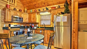 A wooden cabin-style kitchen with a stone table, chairs, a refrigerator, and wooden cabinets. - Game Room & Hot Tub! Black Bear Falls Resort Cabin (Gatlinburg)