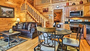 A wooden cabin interior with a living room, dining area, kitchen, and a staircase. - Game Room & Hot Tub! Black Bear Falls Resort Cabin (Gatlinburg)