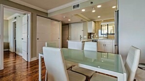 A modern kitchen with white cabinets, a glass dining table, and a view into the adjacent dining area. - Modern Waterfront Hudson Condo w/ Resort Pool! (Hudson)