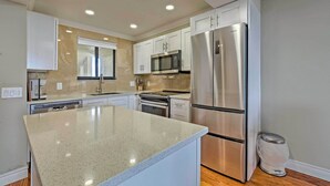 A modern kitchen with white cabinets, stainless steel appliances, and a granite countertop. - Modern Waterfront Hudson Condo w/ Resort Pool! (Hudson)