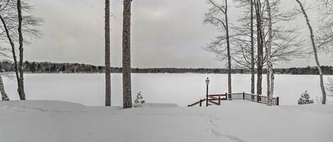 A snowy landscape with a wooden deck and a lamp post.