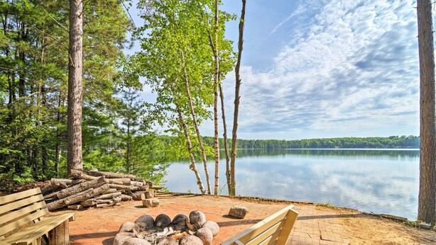 A lakeside campsite with a fire pit, benches, and a view of the lake. - Lakefront Cabin w/ Private Dock & Beach! (Manistique)
