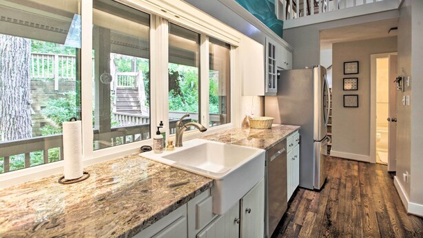 A kitchen with a large window, a sink, and a refrigerator.