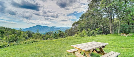 A picnic table in a grassy field with mountains in the background.