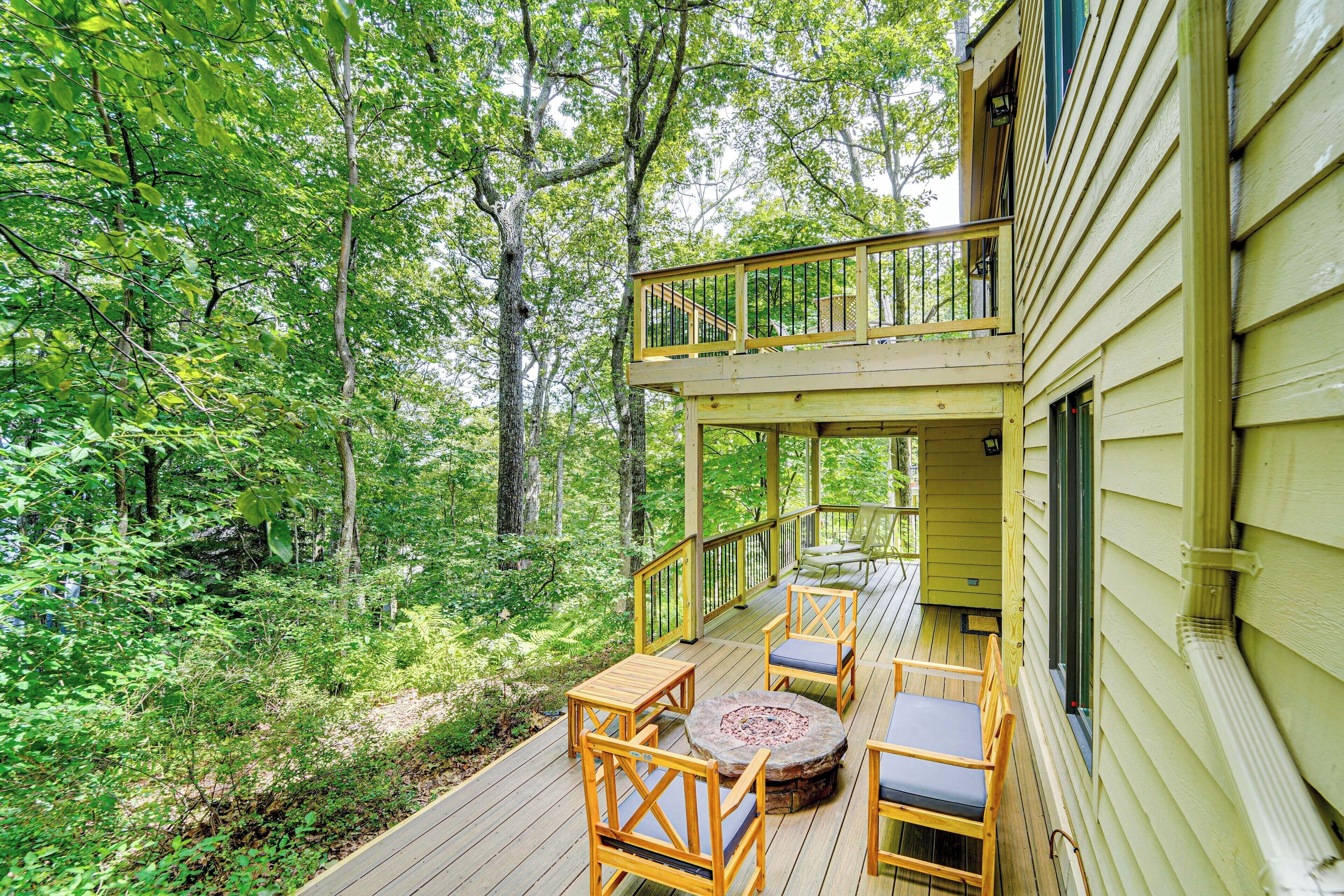 Eine Holzterrasse mit Gartenmöbeln, umgeben von dichtem Wald.