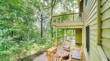 A wooden deck with outdoor furniture, surrounded by dense forest.