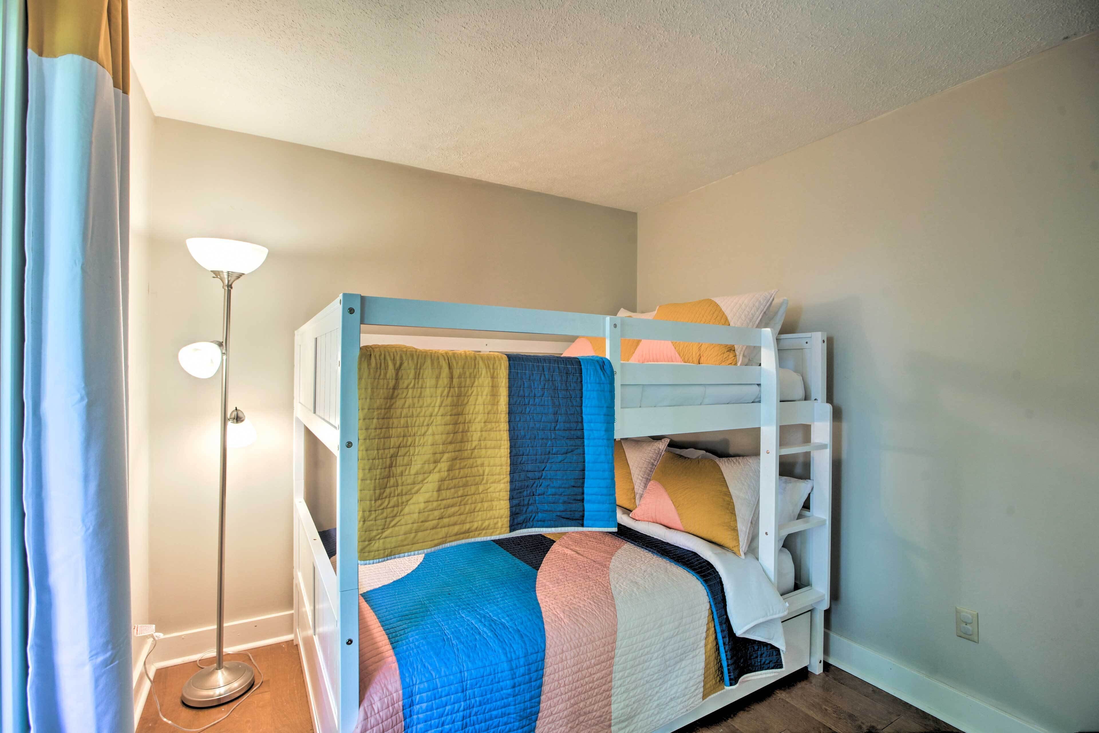 A bunk bed with a quilt, a floor lamp, and a curtain.