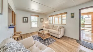 A spacious living room with a beige sofa, a wooden coffee table, and a patterned rug. - Ruidoso Cabin - Walk to Local Park + Downtown (Ruidoso)