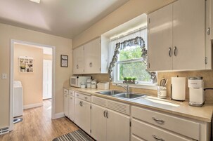 A kitchen with a built-in microwave, a coffee maker, and a window with a curtain.