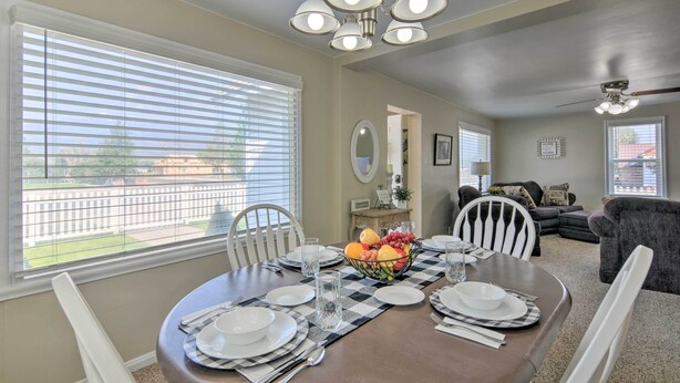 A dining area with a table set for four, a fruit bowl, and a view of the outside through large windows. - Home w/ Fenced Yard by 5 Mighty Nat'l Parks (Circleville)