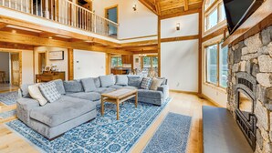 A spacious living room with a large sectional sofa, a wooden coffee table, and a stone fireplace. - Spacious & Secluded Forksville Home: Fire Pit (Forksville)
