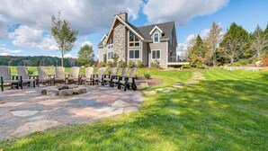 A large house with a stone fireplace, outdoor seating, and a well-maintained lawn. - Spacious & Secluded Forksville Home: Fire Pit (Forksville)
